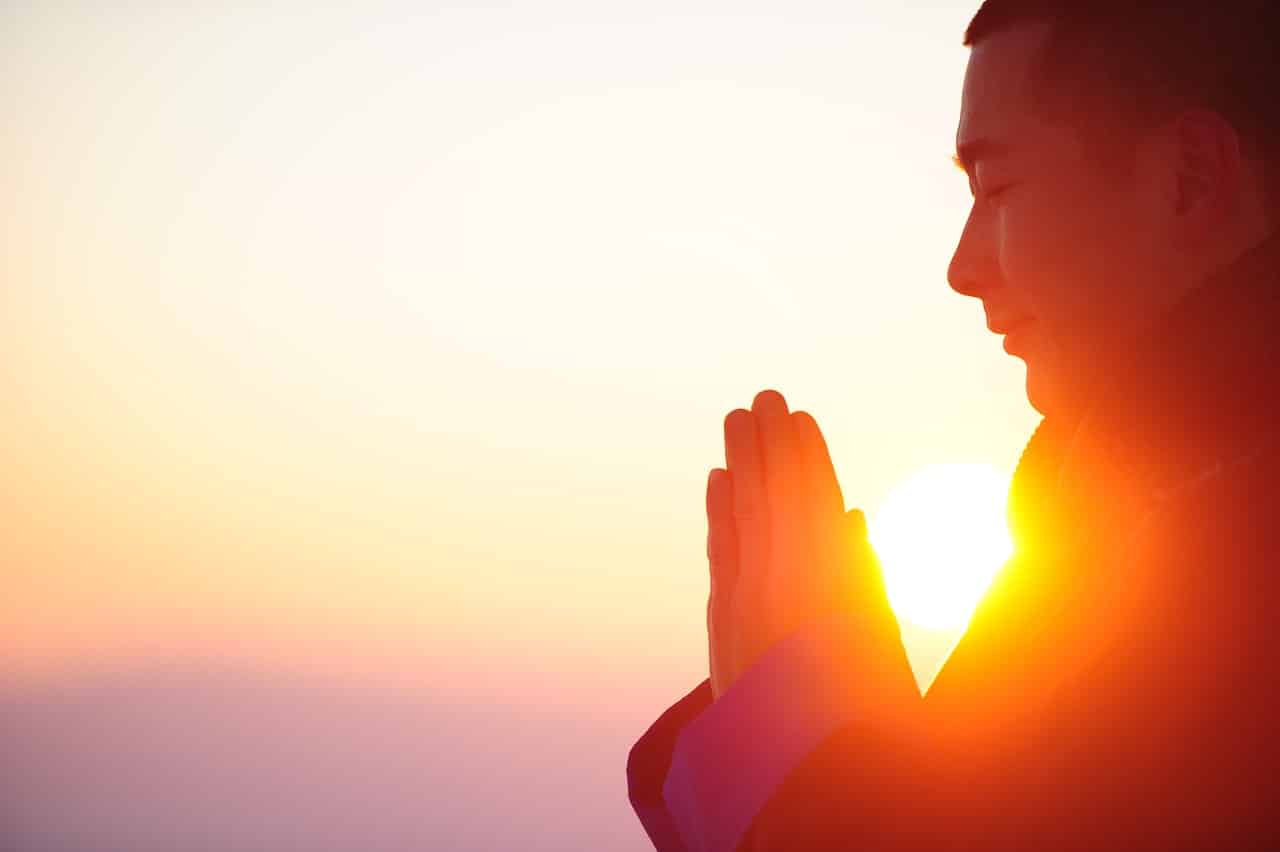 Person i bøn og fordybelse i varmt gyldent lys under en fuldmånemeditation